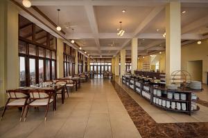 a restaurant with tables and chairs and windows at Astralis Resort Coorg in Madikeri