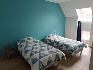 a bedroom with two beds and a blue wall at Gite les trois Petiots in Pirou