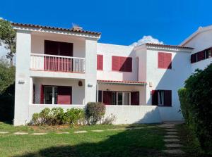 a large white house with red shutters on it at Casa Manacá Vilamoura in Quarteira