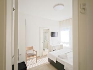 a white bedroom with a bed and a chair at Estelle in Bari