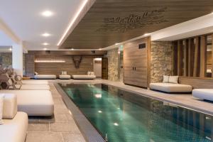 a swimming pool in a hotel with white furniture at Chalet Hôtel & Spa Le Collet in Xonrupt-Longemer