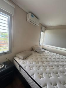 a white bed in a room with a window at Casa quinta a minutos de La Plata in Berisso
