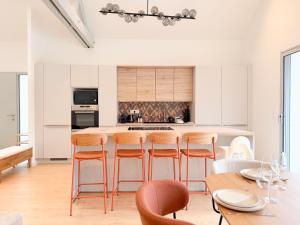a kitchen with white cabinets and a table with stools at Maison Nova in Talant