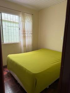 a yellow bed in a room with a window at Casa de temporada in Camboriú