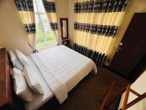 a bedroom with a bed with white sheets and a window at White Hill Villa in Nuwara Eliya