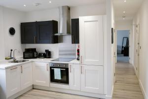 a white kitchen with black cabinets and a sink at Modern - City Centre - Free parking in Norwich +10 photos