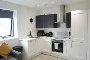 a kitchen with white cabinets and a sink at Modern - City Centre - Free parking in Norwich