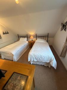 two beds in a attic room with white sheets at Hillhouse in Hythe