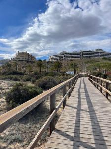 a wooden boardwalk over the beach with buildings in the background at Sunny rest at Pedro's by PORT Holiday Rental in Arenales del Sol