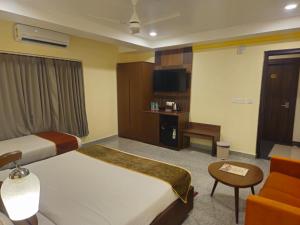 a hotel room with two beds and a chair at Aither in Digha