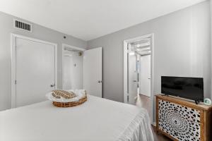 a white bedroom with a bed and a television at Beachfront Condo With Beautiful Sunset in Panama City Beach
