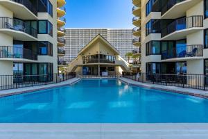 a swimming pool in front of two apartment buildings at Beachfront Condo With Beautiful Sunset in Panama City Beach