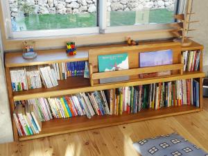 a book shelf filled with books next to a window at Asahinoyado Shidakaji in Nanjo