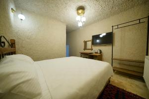 a bedroom with a white bed and a flat screen tv at Nirvana Cave House in Avcılar
