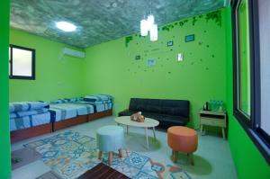 a room with a green wall with a couch and a table at 貓頭鷹森林民宿 in Zhushan