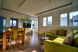 a living room with a green couch and a table at Renome apartmani in Banja Koviljača