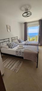 two beds in a bedroom with a view of the ocean at Inas Place in Baška Voda