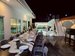 a long long table with chairs and wine glasses at NY grand villa in Nong Prue