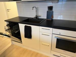 a kitchen with a sink and a black counter top at Moderni Kaksio -Huippu sijainti! in Jyväskylä +2 photos