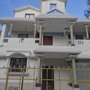 a white house with a fence in front of it at shreejikunj in Bolpur