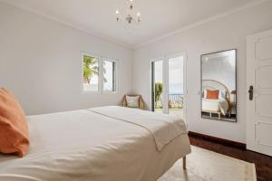 a white bedroom with a bed and a window at Villa Amor Do Mar -180° Sea View, Jacuzzi,Terrace in Funchal