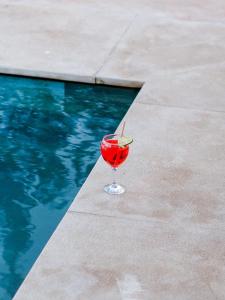 a drink in a glass next to a swimming pool at Palais Dar Souhir in Aït Bou Zguia