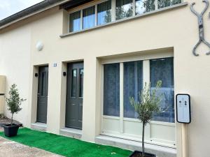 a house with black doors and a green lawn at La Belle Cachette in Matougues