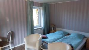 a bedroom with a bed and two chairs and a window at Appartements Haus Hashagen in Oerlinghausen