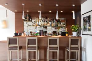 a bar in a restaurant with three bar stools at Best Western Plus Hostellerie Du Vallon in Trouville-sur-Mer