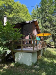 a cabin with a deck with an umbrella at Lou Rigal in Dourbies