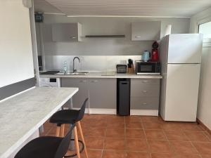 a kitchen with a white refrigerator and two chairs at Le fil à eau 2 pièces centre sud in Rivière-Salée