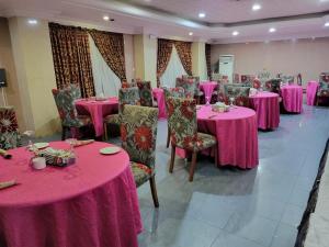 a room with pink tables and chairs with pink tablecloths at Valencia Hotels Abuja in Abuja