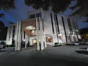 a large white building with columns in a parking lot at Valencia Hotels Abuja in Abuja