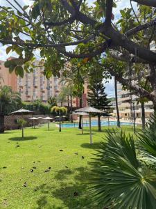 a park with umbrellas and a large building at Costa Relax Beach Apartment with Pool & Tennis in Ifach