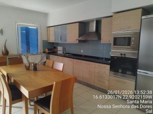 a kitchen with a wooden table and a dining room at Mb HOUSE VILA VERDE RESORT in Prainha