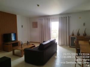 a living room with a couch and a television at Mb HOUSE VILA VERDE RESORT in Prainha