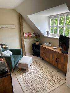 a living room with a green couch and a television at Thatch Cottage Singleton 2 miles from Goodwood in Singleton