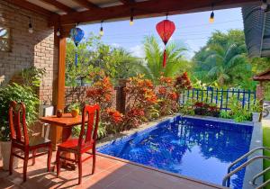 a patio with a table and chairs next to a pool at Family Private Villa Hội An in Hoi An