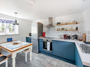 a kitchen with blue cabinets and a wooden table at The Pink Cottage in Bottisham