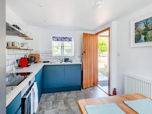 a kitchen with blue and white counters and a table at The Pink Cottage in Bottisham