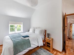 a white bedroom with a bed and a window at The Pink Cottage in Bottisham