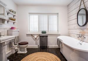 a bathroom with a tub and a toilet and a sink at Blackshore House in Wenhaston +21 photos