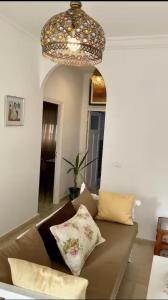 a living room with a brown couch and a chandelier at Studio Authentique à Sidibousaid in Dar Salah Bey +8 photos