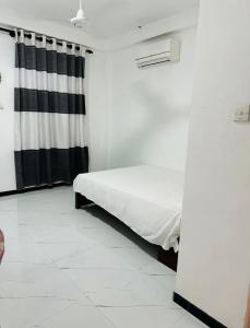 a bedroom with a bed and a black and white curtain at Sirisewana Holiday Inn in Ja-Ela