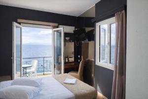 a bedroom with a bed and a view of the ocean at Queens Leriotis Hotel in Piraeus