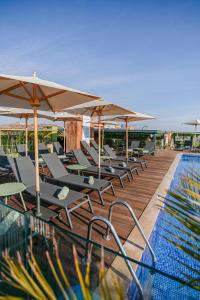 a row of lounge chairs and umbrellas next to a swimming pool at NearYo Hotels in Marrakesh