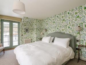 a bedroom with a white bed with floral wallpaper at Schiehallion House in Pitlochry