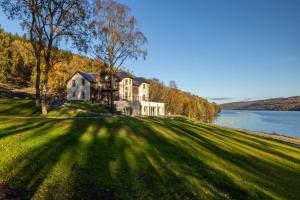 a large house on a hill next to a body of water at Schiehallion House in Pitlochry