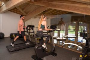 a man and woman riding on exercise bikes in a gym at Chalet Hôtel & Spa Le Collet in Xonrupt-Longemer