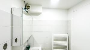 a white bathroom with a sink and a mirror at La Parenthèse Urbaine - T2 Cosy et fonctionnel - Metro 5 Bobigny in Bobigny +13 photos